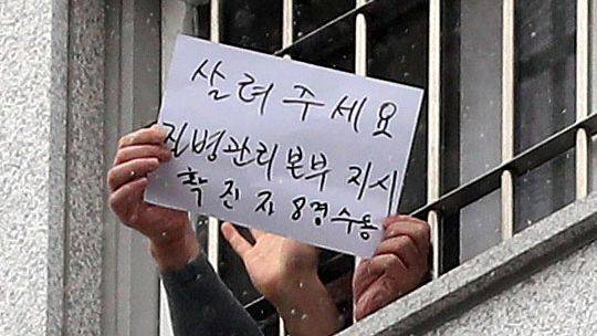 지난해 12월 29일 코로나 집단 감염이 발생한 서울 송파구 동부구치소에서 한 수용자가 '살려주세요'라고 쓴 종이를 취재진에게 흔들고 있다. /뉴시스