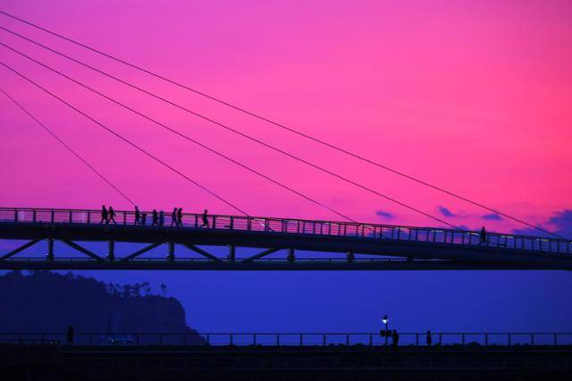 제주 서귀포항에서 바라본 새연교 다리 뒤로 보라빛 노을이 지고 있다.