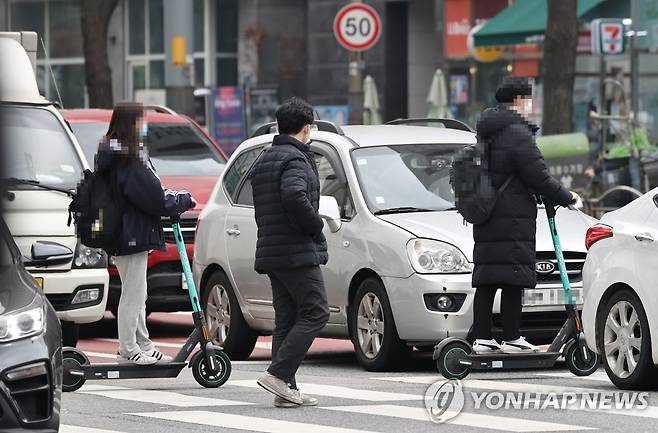 '전동킥보드, 횡단보도를 건널 땐 내려서' (서울=연합뉴스) 윤동진 기자 = 전동킥보드의 자전거도로 주행이 가능해지는 내용 등을 담은 개정 도로교통법·자전거 이용 활성화에 관한 법률이 시행에 들어간 10일 오후 서울 회기역 인근에서 시민들이 전동킥보드를 탄 채 횡단보도를 건너고 있다. 2020.12.10 mon@yna.co.kr