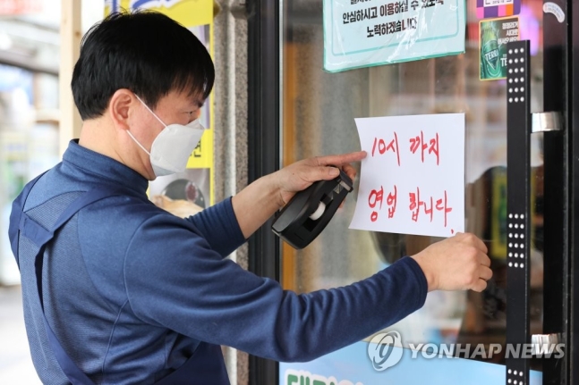 수도권 사회적 거리두기 조치가 2단계로 완화된 15일 서울 중구의 한 호프집에서 사장이 오후10시까지 영업을 알리는 안내문을 붙이고 있다. 2021.2.15. 연합뉴스