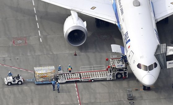 지난 12일 공항 직원들이 일본 나리타 공항에 도착한 코로나19 백신을 운송하고 있다. [로이터=연합뉴스]