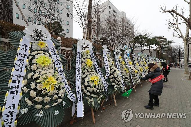 '정인이 살려내라!' (서울=연합뉴스) 백승렬 기자 = 정인 양을 입양한 후 수개월간 학대해 사망에 이르게 한 혐의를 받는 양부모에 대한 2차 공판을 하루 앞둔 16일 오전 서울 남부지검 앞에서 대한아동학대방지협회 회원들이 근조 화환을 정리하고 주변을 청소하고 있다. 2021.2.16 srbaek@yna.co.kr