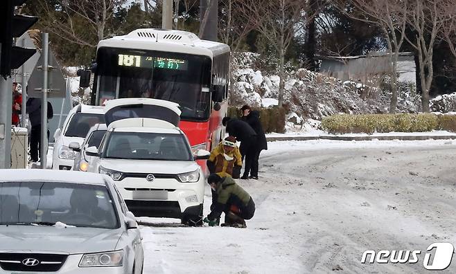 제주도 산지와 동·남·북부에 대설주의보가 발효된 18일 오전 5·16도로 입구에서 운전자들이 차량에 체인을 감고 있다. 현재 1100도로와 5·16도로, 제1산록도로에는 3~5㎝의 눈이 쌓이고 이 중 0.5㎝ 정도가 결빙되면서 차량 통행이 전면 통제된 상태다.2021.2.18/뉴스1 © News1 오현지 기자