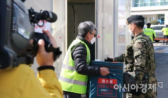 코로나19 백신 수송·보관 통합 모의훈련이 진행되는 19일 오후 2시께 광주광역시 북구보건소 앞에서 백신이 담긴 상자를 관계자가 군의 호위를 받으며 수송 차량에서 내리고 있다.