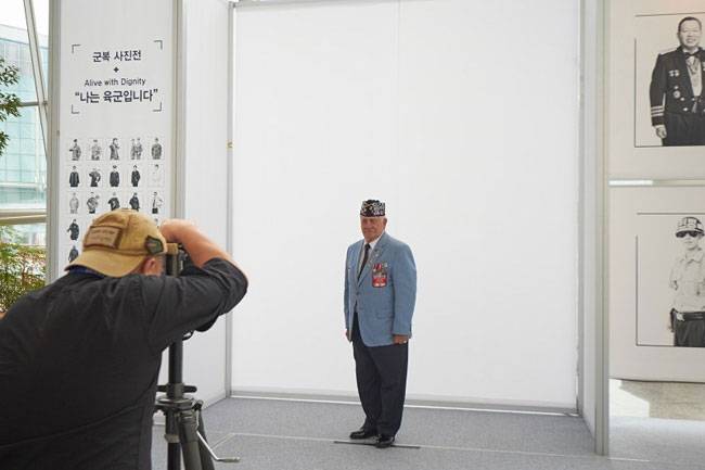 라미 현 작가(왼쪽)가 지난 2016년 경기 일산 킨텍스에서 자신이 개최한 육군 군복사진전을 관람하러 온 미 해병대 참전노병 살 스칼라토(오른쪽)를 촬영하는 모습. 라미 현 제공