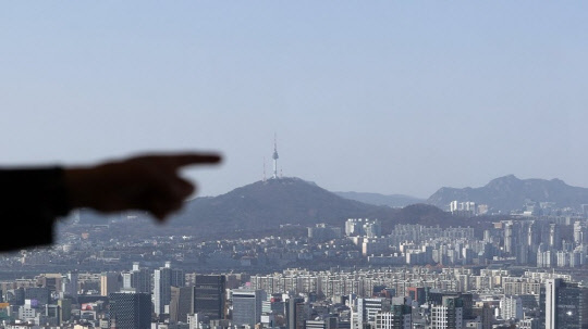 한 시민이 도심 아파트 밀집 지역을 가리키고 있다. <연합뉴스>