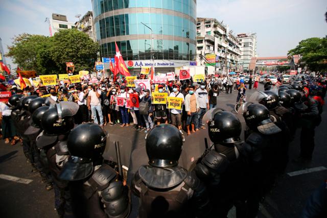 19일 미얀마 양곤에서 각종 손팻말을 든 시위대가 시위 중 경찰과 대치하고 있다. AP 뉴시스