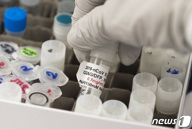 미국 메릴랜드주 노바백스 연구소에서 백신 개발자가 코로나19 백신과 관련된 유리병을 들어올리고 있다. © AFP=뉴스1