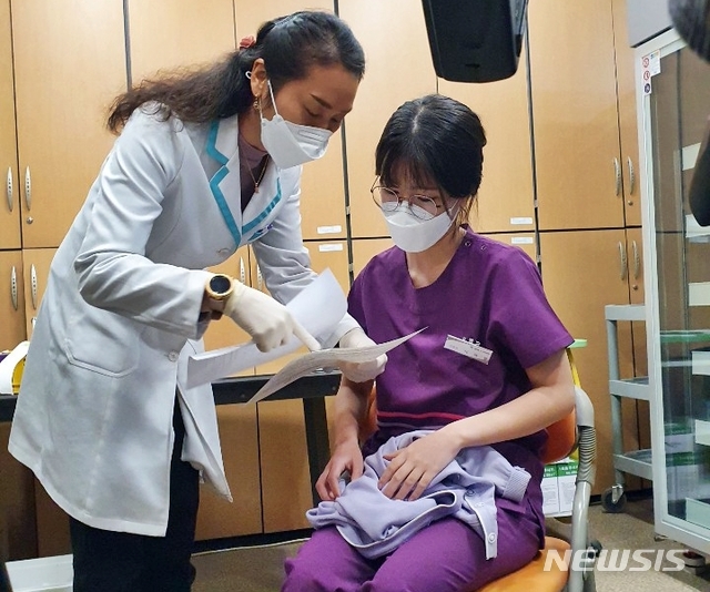 이하현 간호사가 코로나19 백신 접종 전 보건소 직원의 설명을 듣고 있다