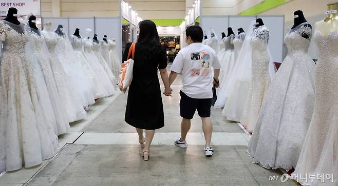 [서울=뉴시스] 이영환 기자 = 19일 오후 서울 강남구 코엑스에서 열린 2020년 추계 제54회 웨덱스코리아 웨딩박람회를 찾은 예비 부부들이 드레스를 살펴보며 이동하고 있다. 2020.07.19.   20hwan@newsis.com