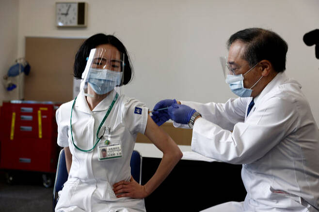 일본에서 의료 종사자에 대한 코로나19 백신 우선 접종이 시작된 국립병원기구 도쿄의료센터에서 한 의료인이 백신을 맞고 있다. 도쿄=AP연합뉴스 