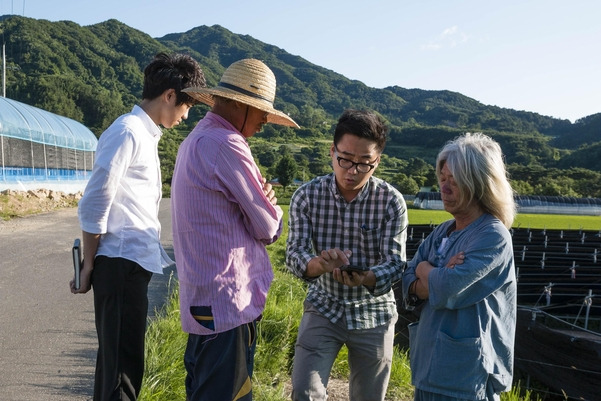 김재훈 식삶(왼쪽에서 세번째) 대표가 산지 농민들과 스마트폰으로 퍼밀 온라인 몰을 보며 대화하는 모습. / 식삶 제공