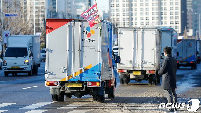 CJ대한통운, 롯데택배, 한진택배, 로젠택배 등 4개 택배사 대리점연합회가 4일 오전 서울 여의도 국회의사당 앞에서 사회적 합의안에 대한 입장을 발표하는 중 이를 지지하는 택배차량들이 국회 앞을 지나고 있다. 2021.2.4/뉴스1 © News1 안은나 기자