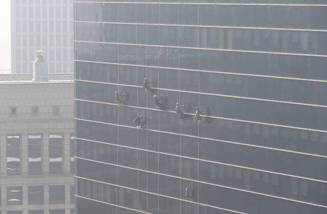 Window washers clean the outside of a building’s windows in Seoul on Thursday. (Kim Hye-yun/The Hankyoreh)