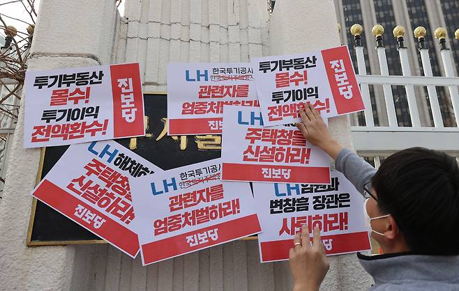 11일 오후 정부서울청사 앞에서 진보당이 연 'LH 직원 투기 의혹 정부합동조사단 1차 조사결과 발표에 따른 기자회견'에서 한 참가자가 '관련자 엄중처벌' 등이 적힌 손피켓을 청사 담장에 붙이고 있다. /연합뉴스
