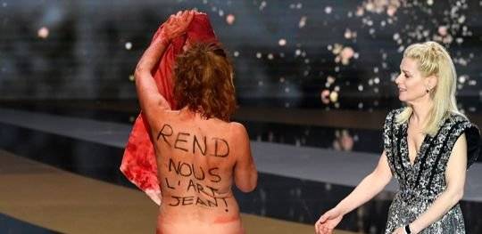 마시에로가 무대에서 나체시위를 벌이자 사회를 맡은 배우 마리나 포와가 당혹스러운 모습으로 바라보고 있다. 마시에로는 등에 프랑스 총리 장 카스텍스를 겨냥해 '예술을 돌려주세요. 장!'이란 문구를 적었다. [로이터=연합뉴스]