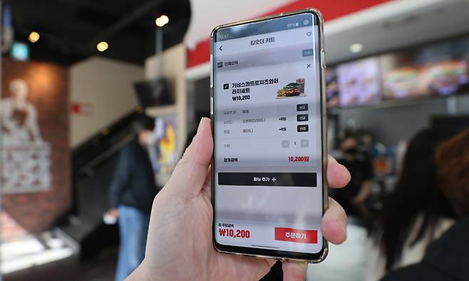 16일 서울의 한 패스트푸드점에서 한 소비자가 모바일앱을 이용해 비대면으로 결제하는 모습을 보여주고 있다. 이날 한국은행은 지난해 일평균 비대면 결제 규모가 8490억원으로 전년 대비 16.9% 늘었다고 밝혔다. 연합뉴스
