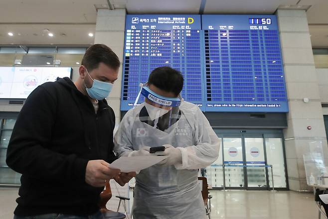 22일 오전 인천국제공항 1터미널 입국장에서 한 외국인이 방역관계자의 안내를 받고 있다. 한국문화광광연구원은 지난해 코로나19 팬데믹으로 전 세계 관광객이 전년보다 70% 넘게 줄어든 것으로 나타났다고 이날 밝혔다. 연합뉴스