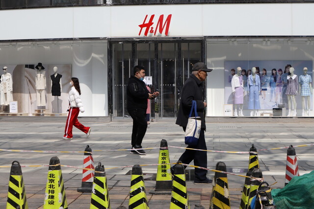25일 중국 수도 베이징에서 시민들이 스웨덴 의류업체 ’에이치 앤 엠’ 매장 앞을 지나고 있다. 베이징/로이터 연합뉴스