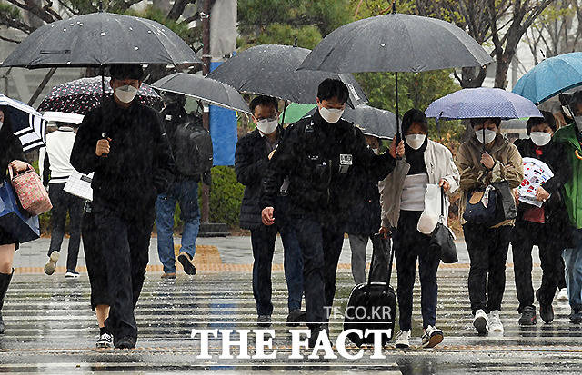 봄비가 내리는 3일 오전 서울 용산역 앞 횡단보도에서 한 경찰관이 우산이 없는 시민에게 우산을 씌워주며 횡단보도를 건너고 있다. /이새롬 기자