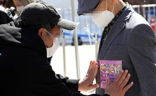 A man receives a sticker showing his time slot for cherry blossom viewing Monday. (Kim Bong-gyu/The Hankyoreh)