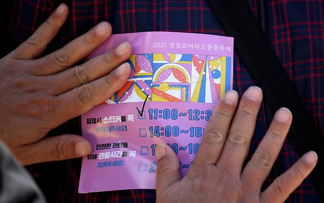 Selected viewers are given a sticker indicating their time slot before they can enter the street. (Kim Bong-gyu/The Hankyoreh)