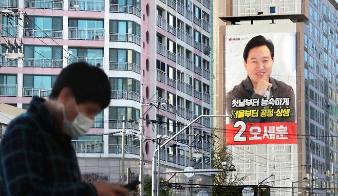오세훈 시장 선거포스터가 걸려 있는 은평구 한 아파트 앞을 주민이 지나고 있다. <매경DB>