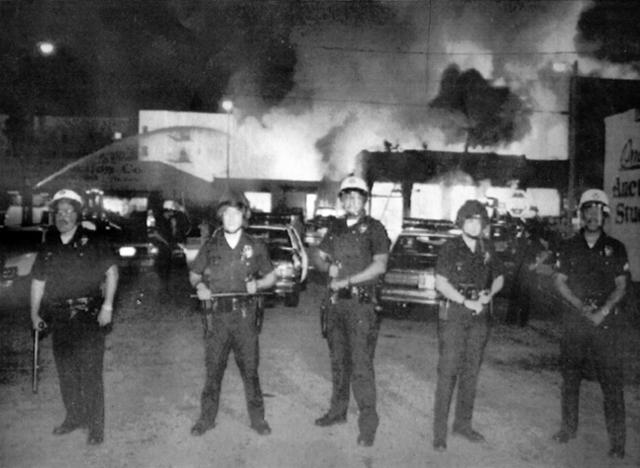 1992년 로스앤젤레스 폭동 당시 경찰들이 불에 타는 건물 앞을 막고 있다. 당시 한인 공동체가 가장 큰 피해를 입었다. 한국일보 자료사진