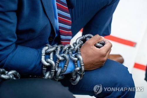 미 조지아주 애틀랜타 의사당에서 한 시위자가 조기투표 시간을 제한하는 입법안에 반대하며 몸에 사슬을 감는 퍼포먼스를 하고 있다. [AFP=연합뉴스]