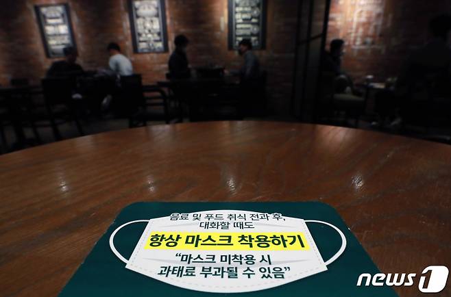 마스크 착용 의무화 조치' 시행 첫날인 12일 오후 서울 시내의 한 커피전문점 테이블에 마스크 착용 안내 문구가 있다. /사진=뉴스1