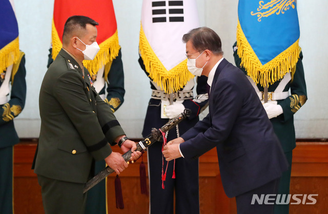 [서울=뉴시스]추상철 기자 = 문재인 대통령이 13일 오후 청와대 본관에서 열린 해병대사령관 진급 및 보직신고식에 참석해 김태성 신임 해병대사령관의 삼정검에 수치를 수여하고 있다. 2021.04.13. scchoo@newsis.com