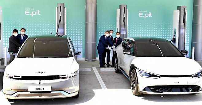 Dignitaries and company officials pose for photos at a ceremony to mark the opening of electric vehicle rapid charging stations at Hwaseong Rest Area on the Seohaean Expressway on Wednesday. (Yonhap)