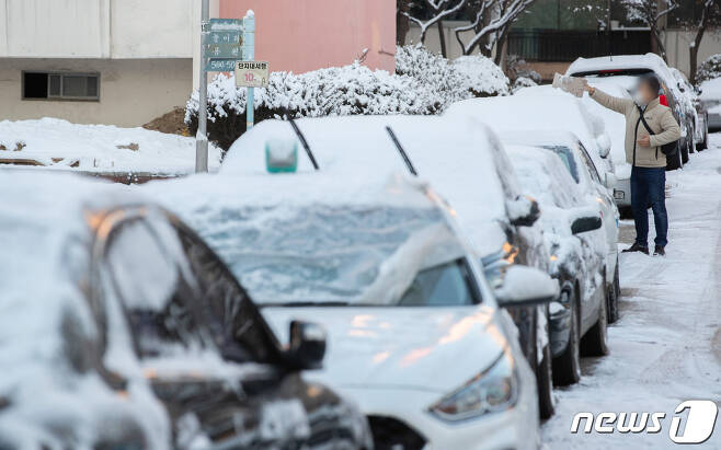 지난밤 수도권을 중심으로 눈이 내린 지난 2월 4일 오전 경기 수원시내의 한 아파트단지에서 출근길 시민들이 차량에 쌓인 눈을 치우고 있다. 2021.2.4/뉴스1 © News1 이재명 기자