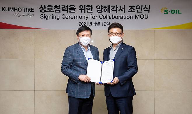 S-Oil Head of Marketing Ahn Jong-bum (right) and Kumho Tire Head of Sales and Marketing Kim Sang-yub pose for a photo after signing a partnership at S-Oil headquarters in Mapo-gu, western Seoul, Monday. (S-Oil)