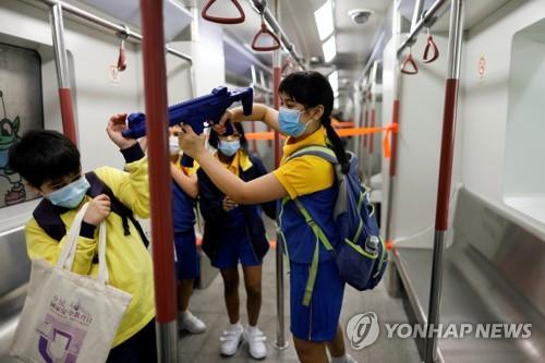 지난 15일 홍콩 '국가안보 교육의 날'에 홍콩 경찰학교를 견학온 아이들이 모형 지하철 안에서 장난감 총을 들고 노는 모습. 연합뉴스