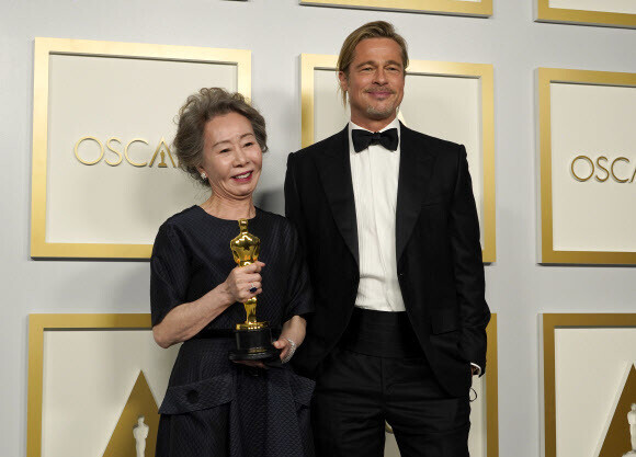 South Korean actor Youn Yuh-jung, winner of the award for best supporting actress for her role as Soon-ja in \"Minari,\" poses for a picture with Brad Pitt, who presented the best supporting actress award, in the press room at the Oscars on Sunday, at Union Station in Los Angeles, California. (Yonhap News)