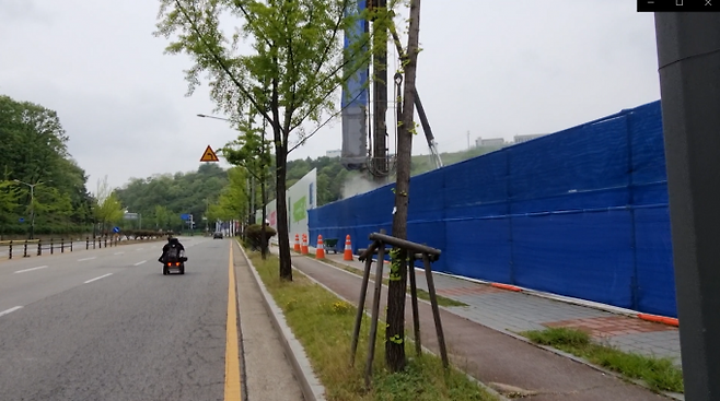 공사현장의 비산먼지를 피해 휠체어를 탄 한 장애인이 차도를 달리고 있다.   박진영 기자