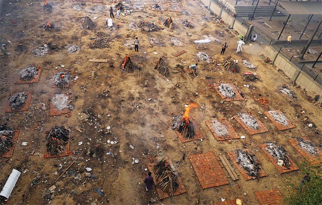 지난달 21일(현지 시각) 인도 뉴델리의 한 화장터에서 장례용 화약을 태우는 가운데 코로나19로 사망한 주검이 누워 있다. /블룸버그 EPA 연합뉴스