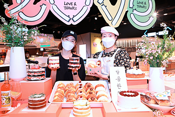 Employees pose with cakes and donuts at Lotte Department Store's Jamsil branch in southern Seoul on Monday. The department store has opened a pop-up shop selling cakes and donuts from different popular stores in Seoul until this weekend. [YONHAP]