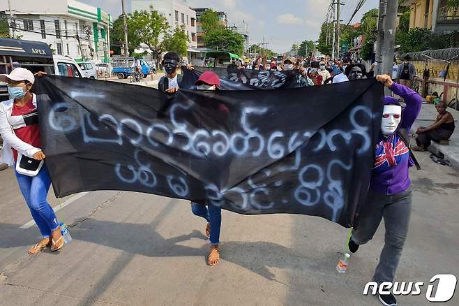 1일(현지시간) 시위대들이 '우리는 민주주의를 원한다'라고 적힌 플랜카드를 들고 양곤 시내를 걷고 있다. © AFP=뉴스1 © News1 원태성 기자