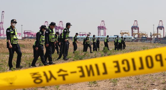 경찰관들이 12일 인천시 연수구 송도신항의 한 공터에서 4월 22일 인천 한 노래주점에서 실종된 A씨(40대)의 시신을 찾기 위해 수색하고 있다. 뉴스1