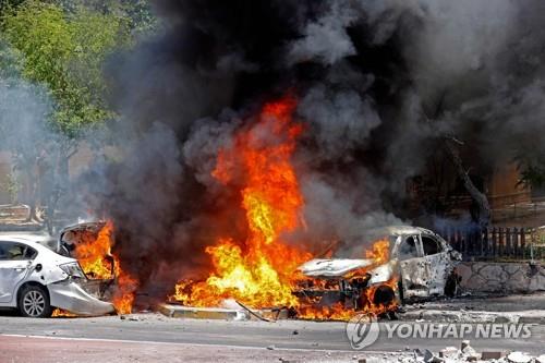 가자지구발 로켓포가 떨어진 이스라엘 아슈켈론의 주차장에서 불타는 자동차 [AFP=연합뉴스]