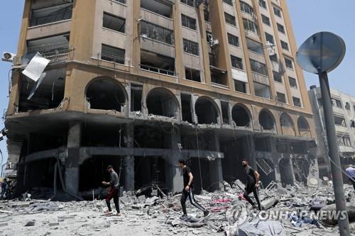 12일 가자시티에서 이스라엘 공습에 파괴된 건물 잔해를 사람들이 점검하고 있다. [AP=연합뉴스]