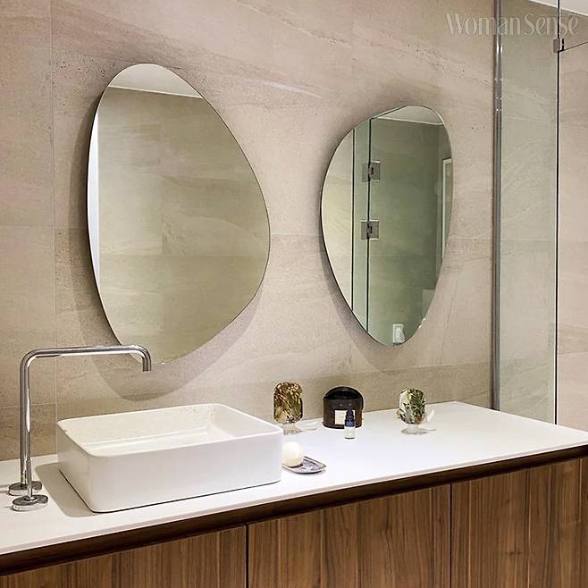 동그스름한 거울과 원목 하부장이 멋스러운 욕실.