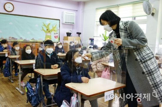 서울의 한 초등학교에서 담임교사가 등교한 학생들의 열을 측정하고 있다./사진공동취재단