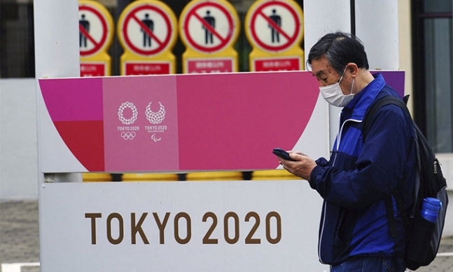 한 남성이 2020 도쿄올림픽·장애인올림픽 홍보물 앞을 지나가고 있다. 도쿄=AP뉴시스