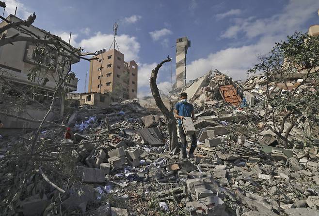 한 팔레스타인 소녀가 18일(현지시간) 이스라엘의 공습을 당해 무너진 건물 잔해에서 쓸만한 물건을 찾아보고 있다.(사진=AFP제공)