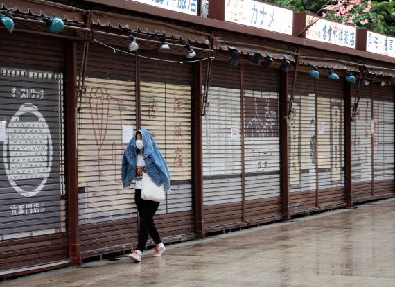 지난 7일 한 여성이 외투로 비를 가리며, 도쿄 유명 관광지인 아사쿠사 상점가를 거닐고 있다. 긴급사태 선언으로 상점가들이 대부분 문을 닫았다. 로이터 뉴스1