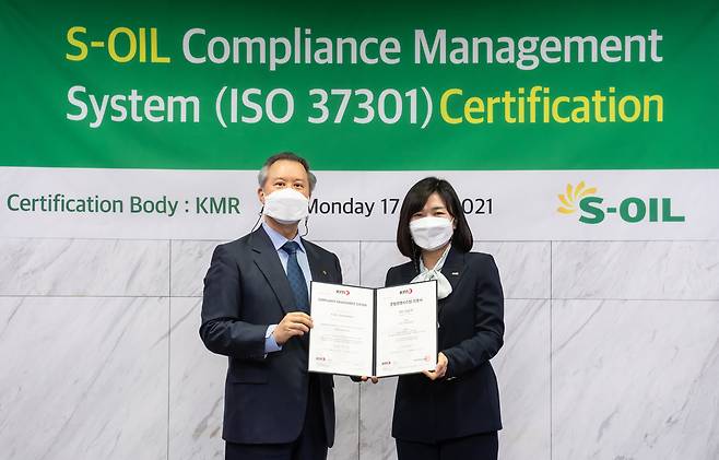 S-Oil Legal & Compliance Head and Senior Vice President Park Sung-woo (left) is awarded ISO 37301 compliance management system certification from the Korea Management Registrar President Hwang Eun-ju at S-Oil headquarters in Mapo-gu, western Seoul, Monday. (S-Oil)