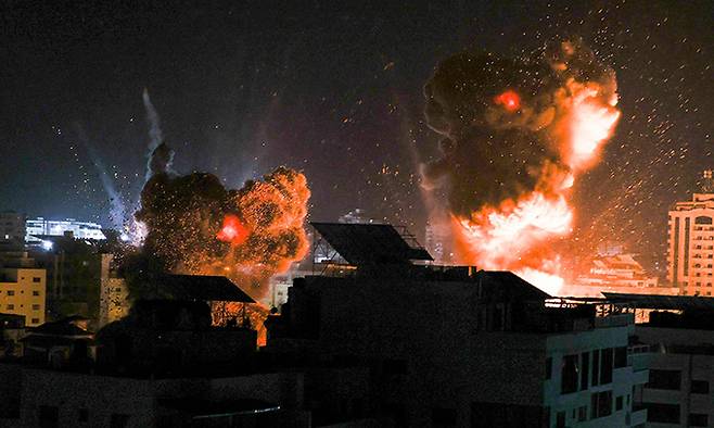 팔레스타인 자치지역인 가자지구 중심도시 가자시티에서 18일 새벽(현지시간) 이스라엘 전투기의 공습으로 화염과 연기가 밤하늘에 치솟고 있다. 가자시티=AFP연합뉴스